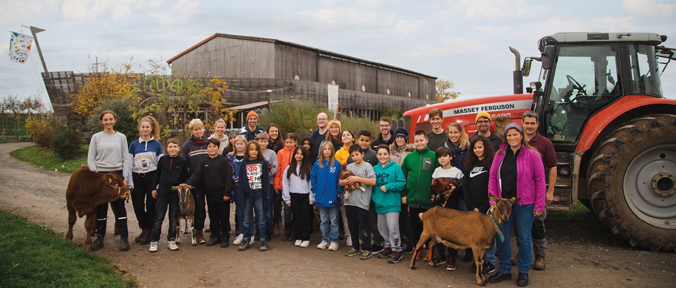 Eine Gruppe aus Kindern, Betreuern und den tierischen Anwohnern des Schulbauernhofs Zukunftsfelder